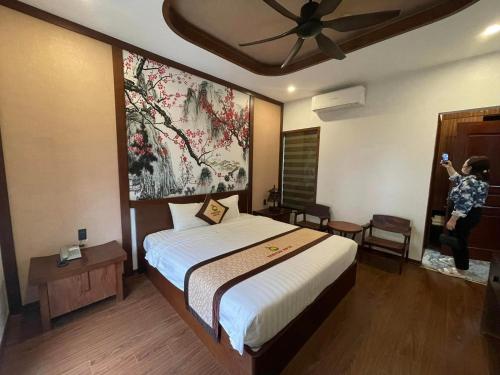 a bedroom with a bed and a painting on the wall at Sunstar Hotel in Ha Long