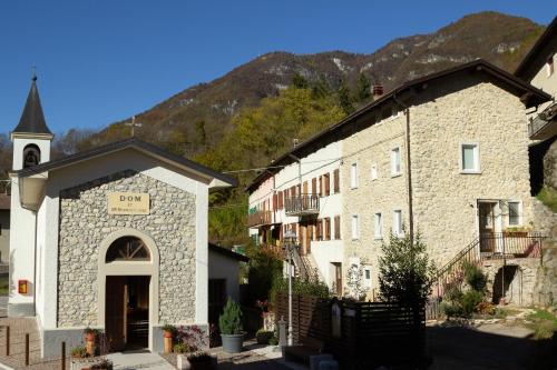 eine Kirche neben einem Gebäude mit einem Turm in der Unterkunft Valdastico Casetta in sasso con giardino in Pedemonte