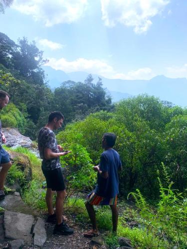a group of people standing on top of a mountain at Knuckles Backpackers Hut with waterfall view in Kaduwela