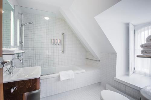 a white bathroom with a tub and a sink at Monastère des Augustines in Quebec City