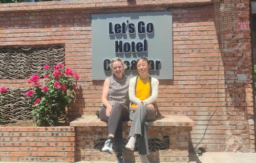two women sitting on a brick bench in front of a hotel at Beijing MutianyuGreat Wall Let'sgo Hotel&Bar in Huairou