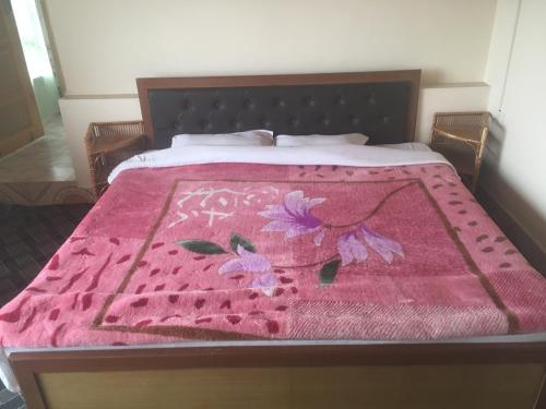a bed with a pink blanket on top of it at Alifland in Srinagar