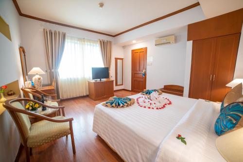 een slaapkamer met een wit bed en een televisie bij Oscar Saigon Hotel in Ho Chi Minh-stad