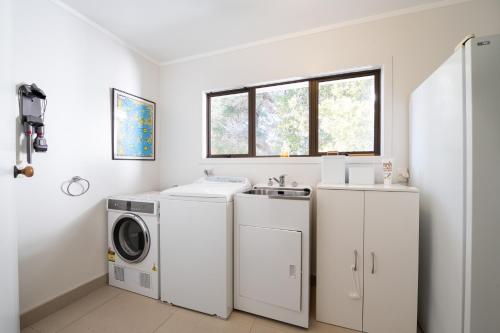 a white laundry room with a washer and dryer at River Palms Retreat - Paihia Holiday Home in Haruru