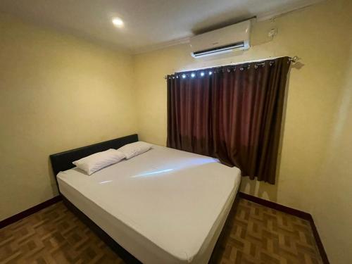 une chambre avec un lit blanc avec une fenêtre dans l'établissement RedDoorz at Jalan Sam Ratulangi Manado, à Manado