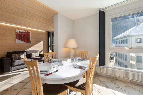 Appartement L'Outa 209 - Happy Rentals في شامونيه مون بلان: غرفة طعام مع طاولة بيضاء وكراسي