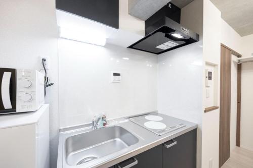 a small kitchen with a sink and a microwave at Ferio kamata III in Tokyo