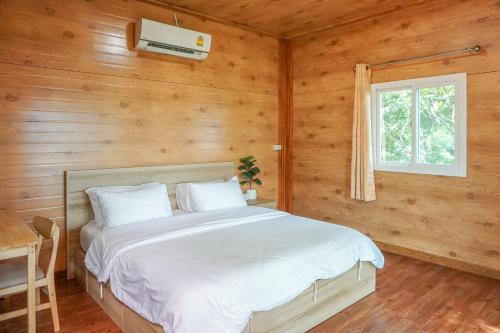 a bedroom with a bed in a wooden cabin at Beung Sampathuan Nakornchaisri Resort in Ban Laem Bua