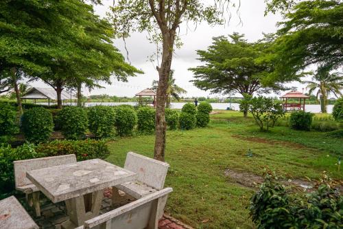a picnic table and bench in a park with trees at Beung Sampathuan Nakornchaisri Resort in Ban Laem Bua