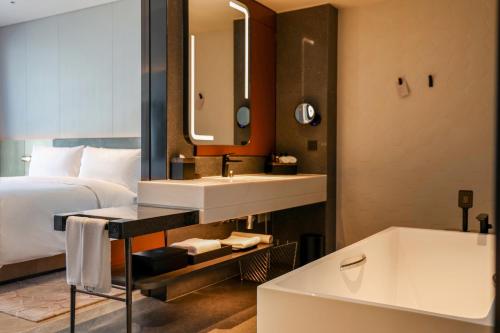 um quarto de hotel com uma cama, um lavatório e uma banheira em AC Hotel by Marriott Chengdu North em Chengdu