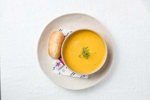 a white plate with a bowl of soup and a piece of bread at Killara Hotel & Suites in Killara