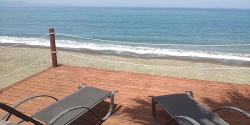 two chairs sitting on a wooden deck near the beach at Uniquely located on the beach in Ayia Marina