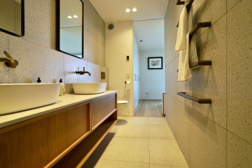 a bathroom with two sinks and a mirror at Nikau Estate, Oneroa - Be My Guest in Matiatia Bay
