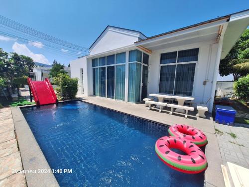 a swimming pool with two inflatables in front of a house at บีชทาวน์ ชะอำ พูลวิลล่า ห่างหาดชะอำ2กม Beach town cha-am poolvilla from Cha-Am beach just 2km in Cha Am