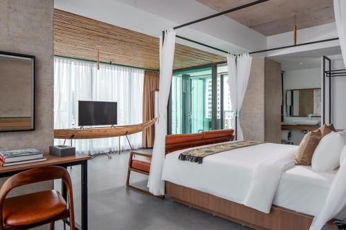 a bedroom with a bed and a desk and a television at CHECK inn Phnom Penh Royal Palace in Phnom Penh