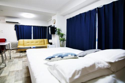 a bedroom with blue curtains and a bed and a couch at 大森ホテル ビッグフォレスト in Tokyo