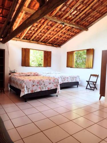 a bedroom with two beds in a room with windows at Casa Rosa Chá em Lençóis in Lençóis