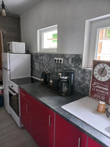 a kitchen with red cabinets and a white refrigerator at Gite des forets in Trésauvaux
