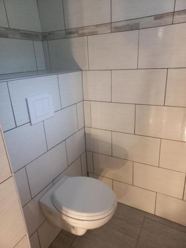a bathroom with a white toilet in a tiled wall at Gite des forets in Trésauvaux