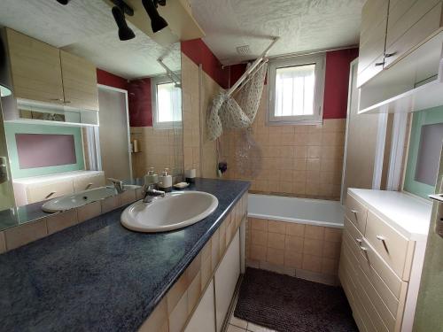 une grande salle de bain avec un lavabo et un miroir dans l'établissement L' Albizia, à Sarzeau