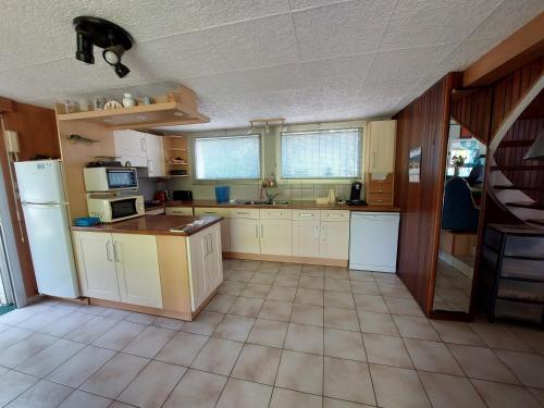 une grande cuisine avec des armoires et des appareils blancs dans l'établissement L' Albizia, à Sarzeau