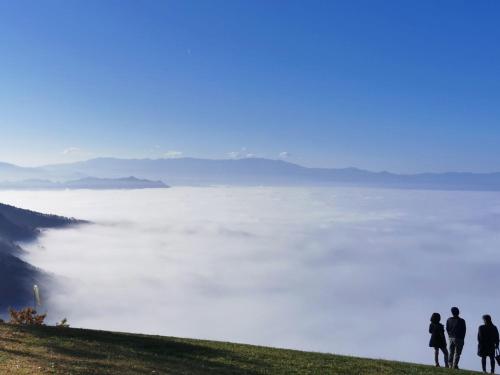 three people standing on top of a hill overlooking a fog covered valley at Itoya Ryokan in Nanyo