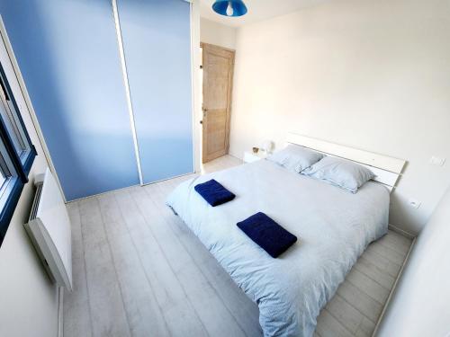 - une chambre dotée d'un lit blanc avec des oreillers bleus dans l'établissement Maison spacieuse, à Moyon