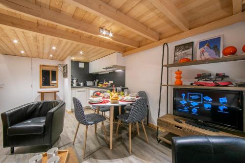 sala de estar con mesa, sillas y TV en Résidence Grand Roc - Ancolies 207 - Happy Rentals en Chamonix-Mont-Blanc