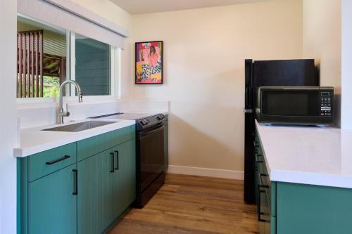 a kitchen with a sink and a microwave at Royal Lahaina Resort & Bungalows in Lahaina