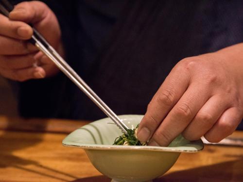 a person is eating a bowl of food with chopsticks at Itoya Ryokan in Nanyo