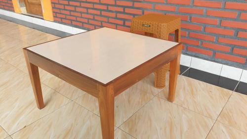 a table and a chair sitting next to a brick wall at SPOT ON 93999 Kost Ibu Joko Syariah in Lawang