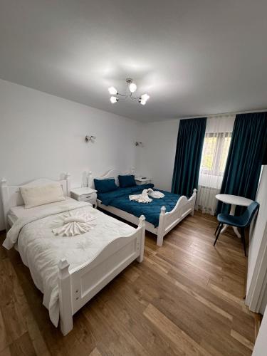 a bedroom with two beds and a table and a chair at Casa Croitoru Maramureş in Onceşti