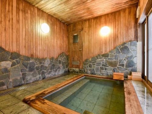 a swimming pool in a room with a stone wall at Itoya Ryokan in Nanyo