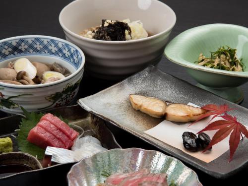 a table topped with bowls and plates of food at Itoya Ryokan in Nanyo
