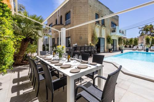 una mesa y sillas en un patio junto a la piscina en Luxurious Villa 5 BR, Pool, 3min from St Julian's en Is-Swieqi