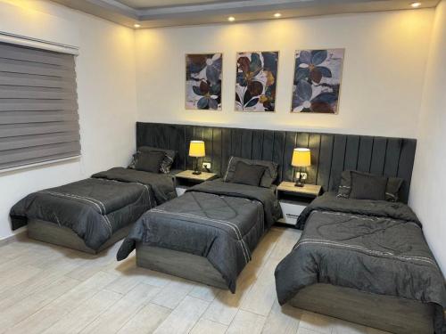 une chambre avec trois lits et deux tables dans l'établissement Alma Private Villa, à Jerash