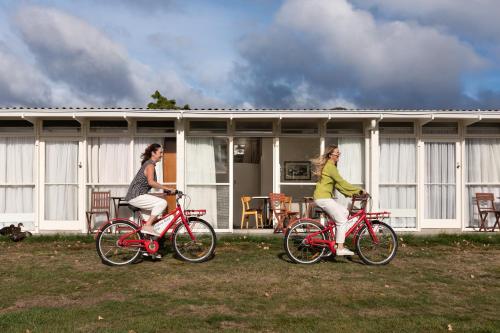 two women riding bikes in front of a house at Riverfront Motel & Restaurant in Hobart