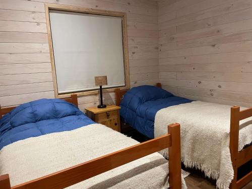 two beds in a room with wooden walls at Cabaña Azul in Riñinahue