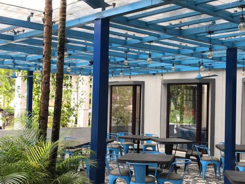a patio with tables and chairs under a blue pergola at Fortune Valley View, Manipal - Member ITC Hotels' Group in Manipala