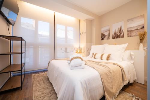 a bedroom with a large white bed with white pillows at Le Petit Apartamento in Gijón