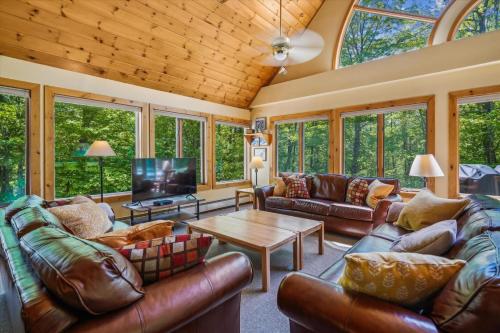 a living room with leather couches and a wooden ceiling at Sunburst in Killington