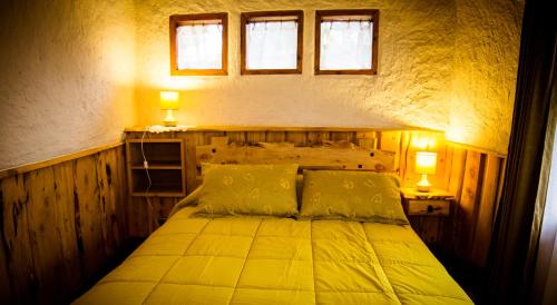 a bedroom with a bed with two lights and two windows at Complejo Cabañas Quilamalen in Villarrica