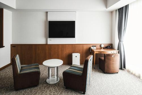 Habitación de hotel con TV, mesa y sillas en Vessel Hotel Campana Okinawa en Chatan