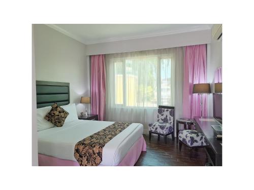 a hotel room with a bed and a chair at Fiesta Garden Hotel in Vigan