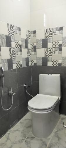 a bathroom with a toilet and a tile wall at Limewood homestay in Almora