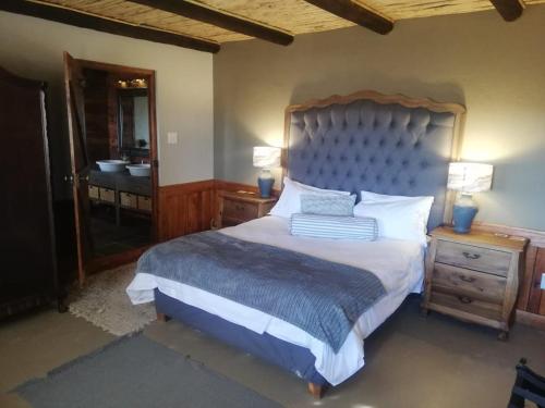 Nuwefonteinskop Lodge في Kotzesrus: غرفة نوم بسرير وحمام مع حوض