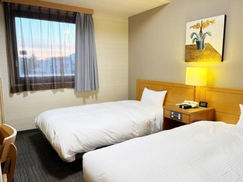 a hotel room with two beds and a window at Hotel Route-Inn Ogaki Inter in Ogaki