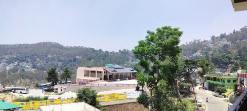a view of a town with a tree and buildings at Limewood homestay in Almora