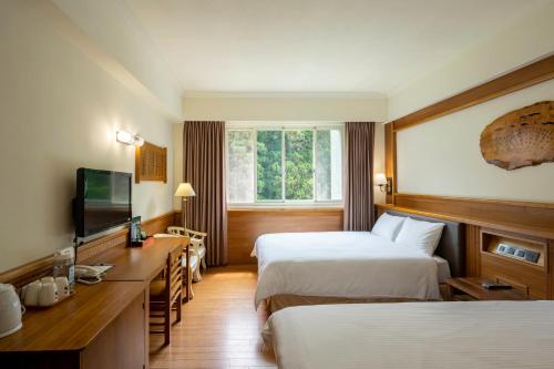 een hotelkamer met 2 bedden en een televisie bij Ginkgo Hotel in Lugu