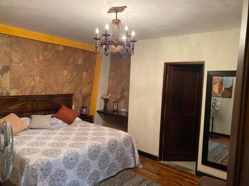 a bedroom with a bed and a chandelier at Hotel Casa Victoria in Antigua Guatemala